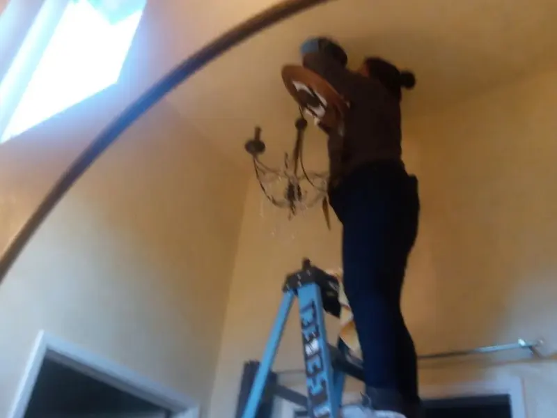 Electrician installing a chandelier in a Manchester residence